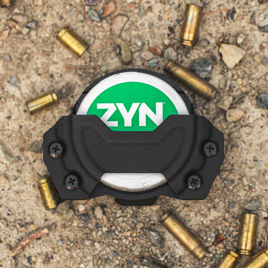 pouch holster with the 'ZYN' logo on it, placed on a surface with scattered bullet casings.