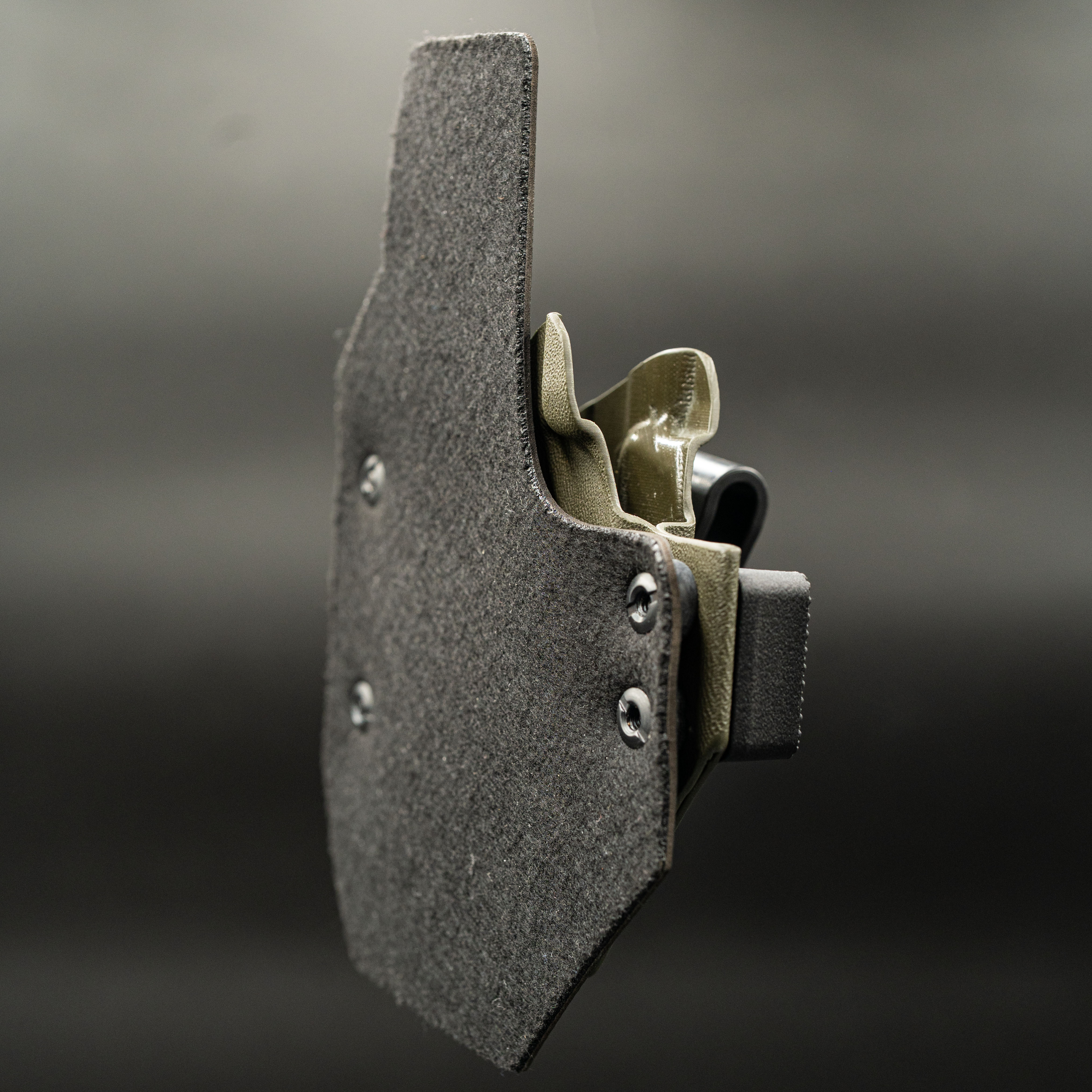 Outlaw IWB(inside the waistband) holster with a leather back on a dark background