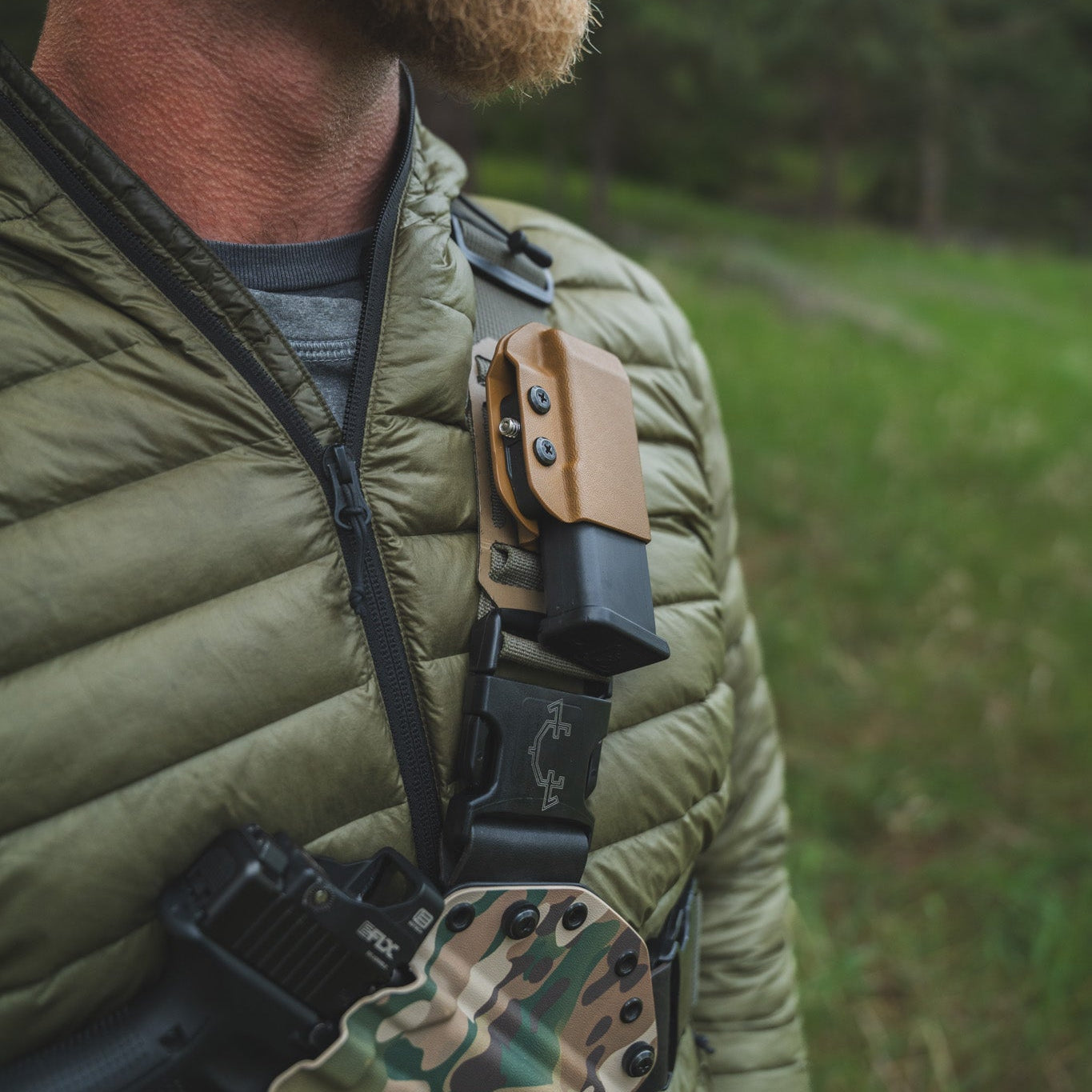 Man wearing a green jacket with a rifle on his back in a forest setting