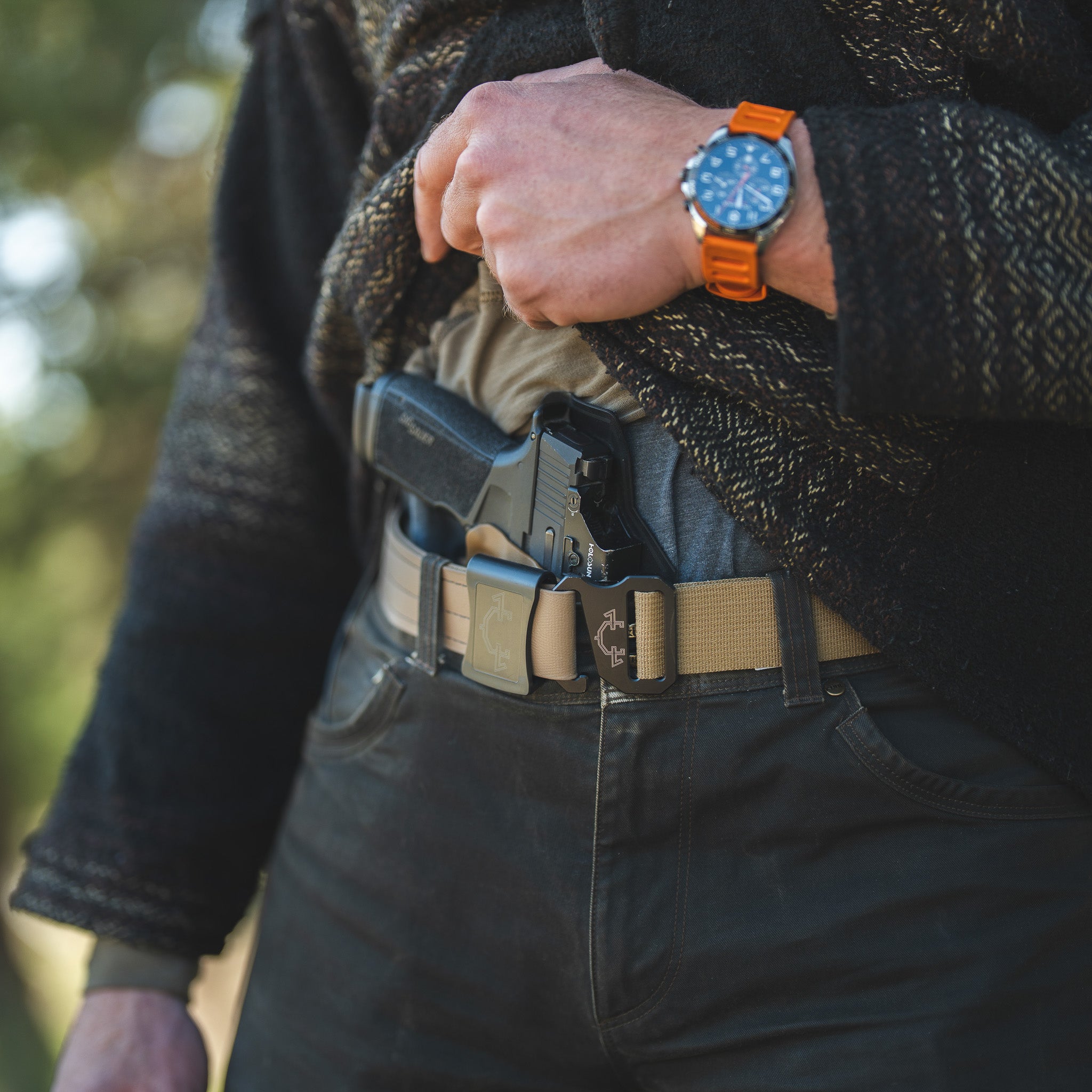 Person wearing a invader concepts tactical EDC belt with a IWB(inside the waistband) holster and an orange watch.