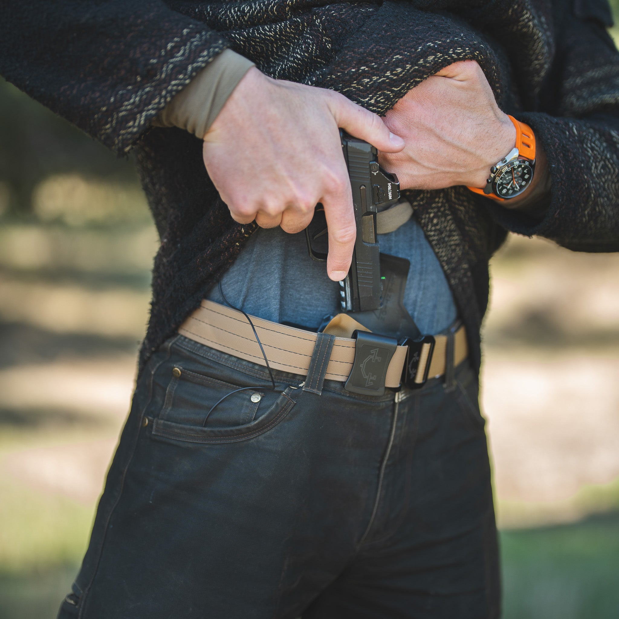 Person with a gun in an IWB(inside the waistband) holster on a blurred natural background