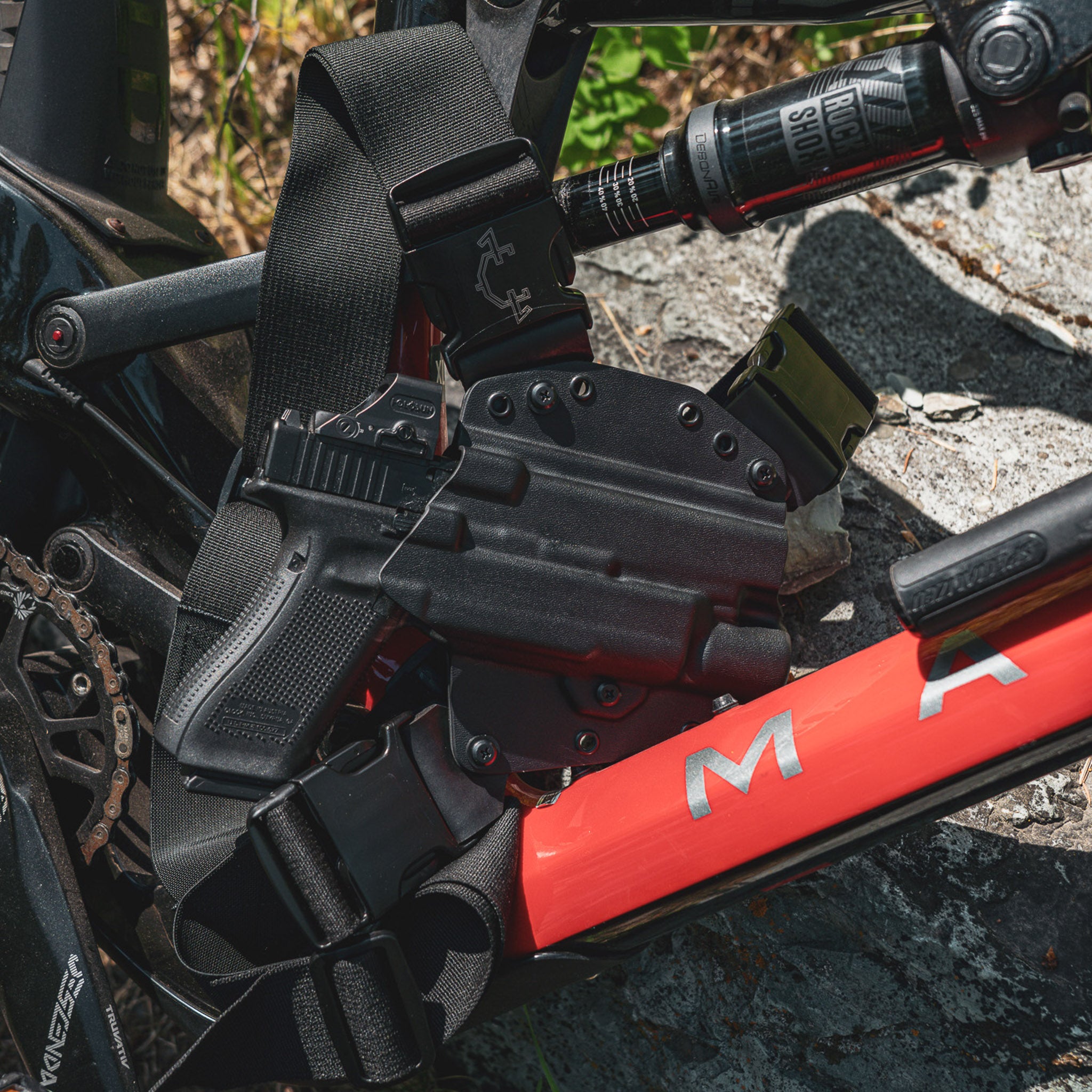 Black recon chest holster with light options next to a red bicycle
