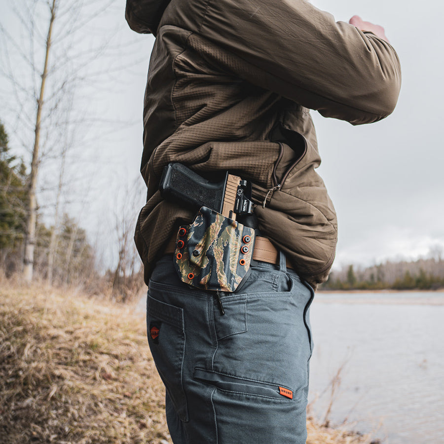 Person in outdoor setting with an outlaw owb(outside the waistband) holster