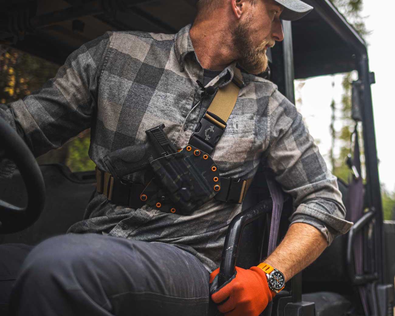 Man wearing recon chest holster while riding a side by side