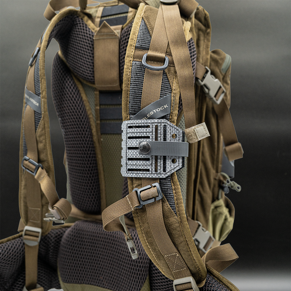 Tactical backpack with multiple straps with a blade lok attached and a visible brand tag on a dark background
