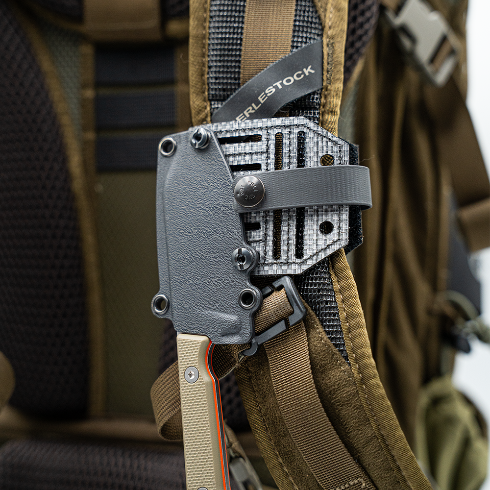 tactical knife sheath attached to a brown backpack strap with a blade lok