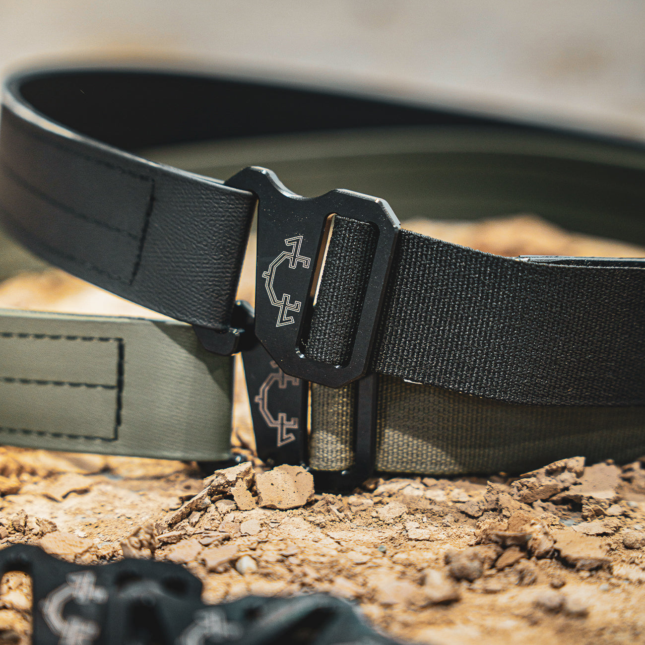 Black and OD Green edc(everyday carry) belt with a buckle on a rocky surface
