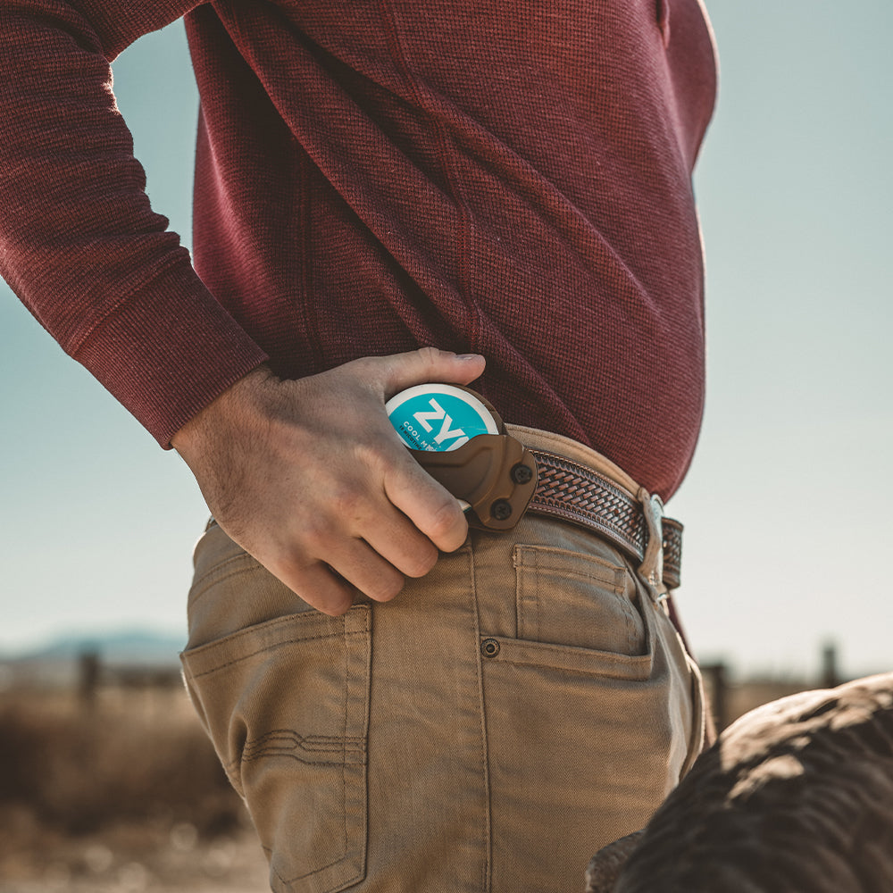 Person in a red sweater and brown pants with a pouch holster attached to an edc(everyday carry) belt
