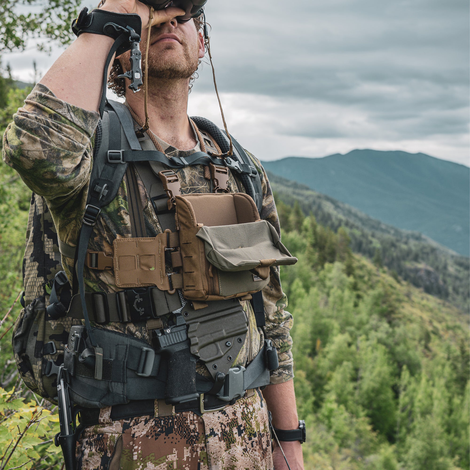 Person looking through binoculars while wearing a Guide torso holster.