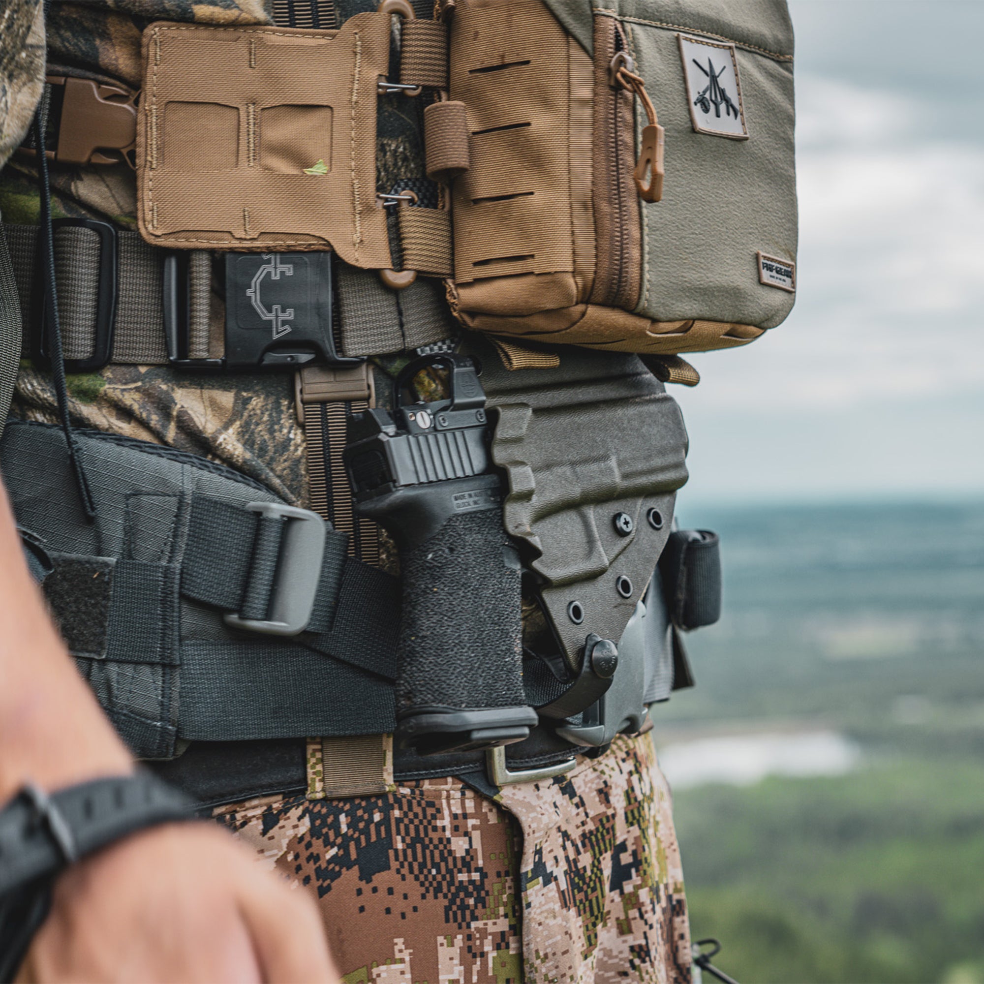 person wearing a FHF bino harness on top of a Guide Torso holster, in a rock landscape.