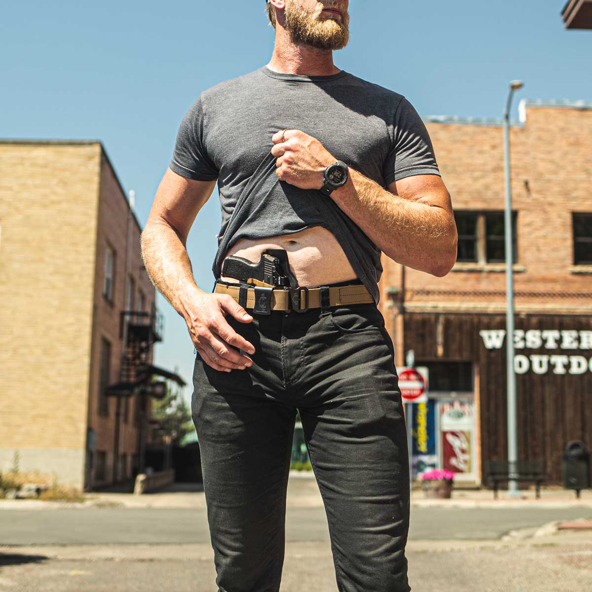 Man wearing an edc(everyday carry) belt and outlaw iwb(inside the waistband) with a western town background