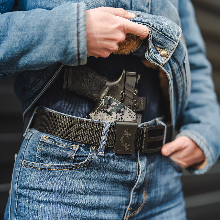 Person wearing an EDC belt with an outlaw iwb(inside the waistband) holster, holding a jacket open.