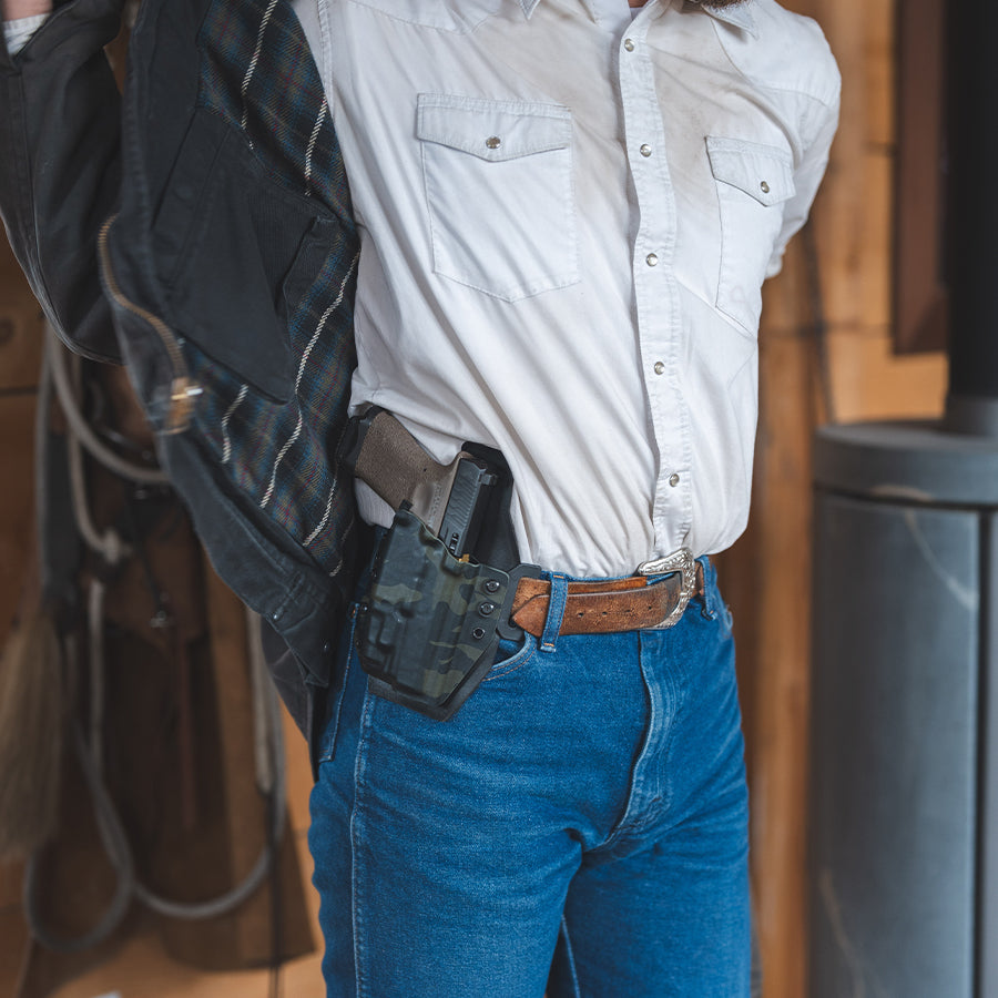 Person wearing a white shirt and blue jeans with an outlaw owb(outside the waistband)