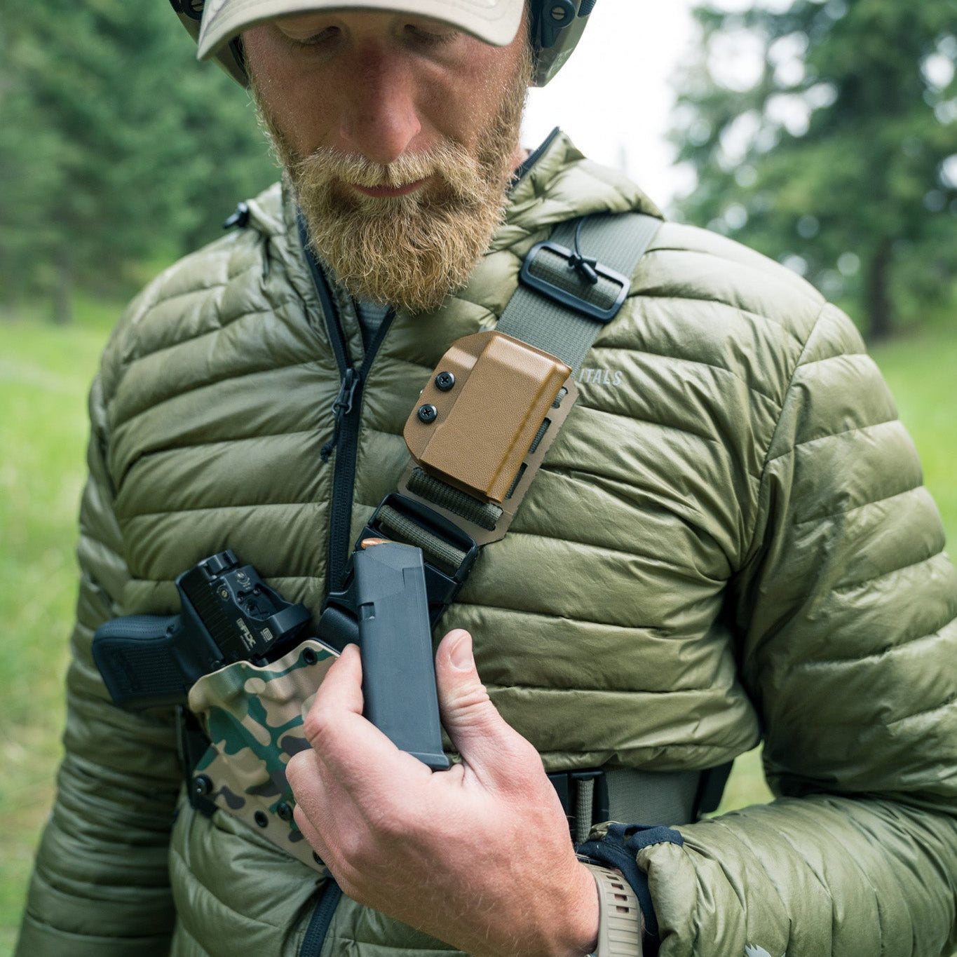 Man in tactical gear holding a rifle in a forest setting