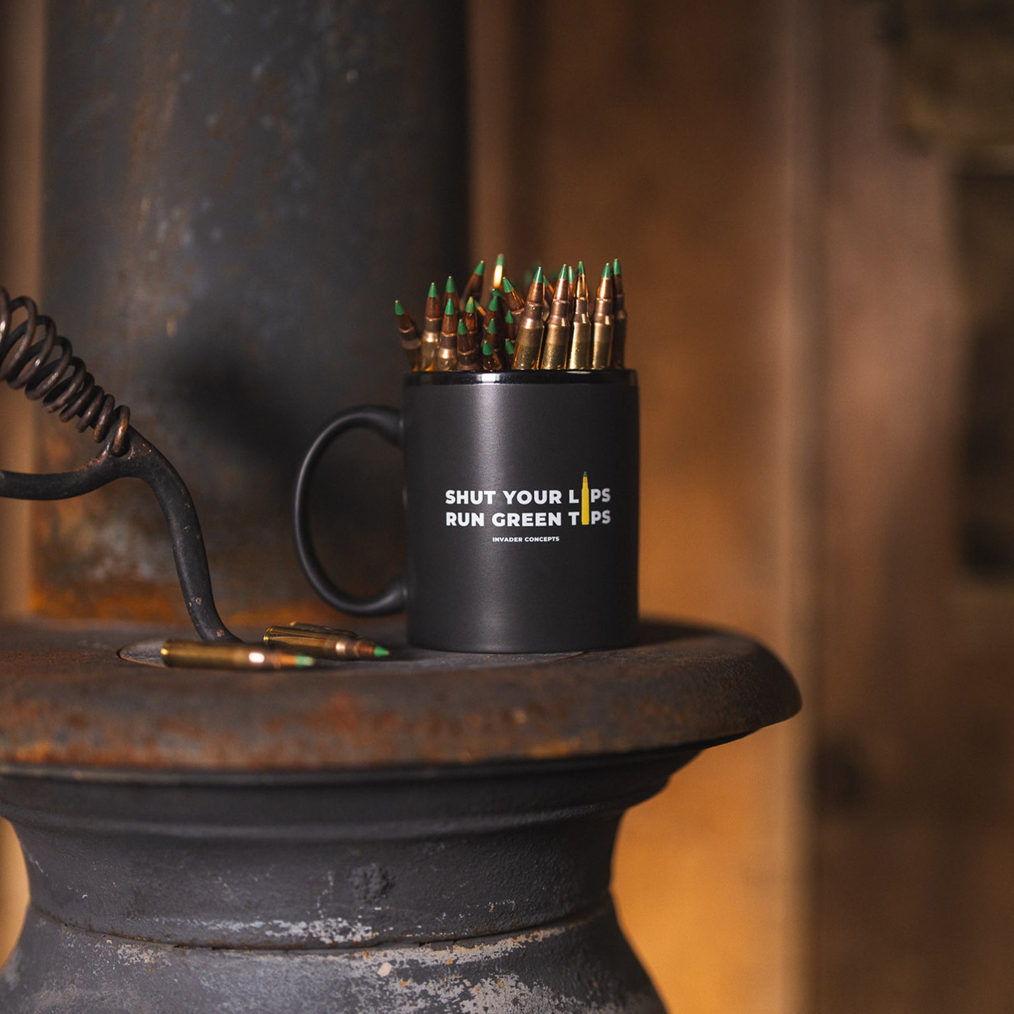Black mug with bullet casings and text on a rustic surface