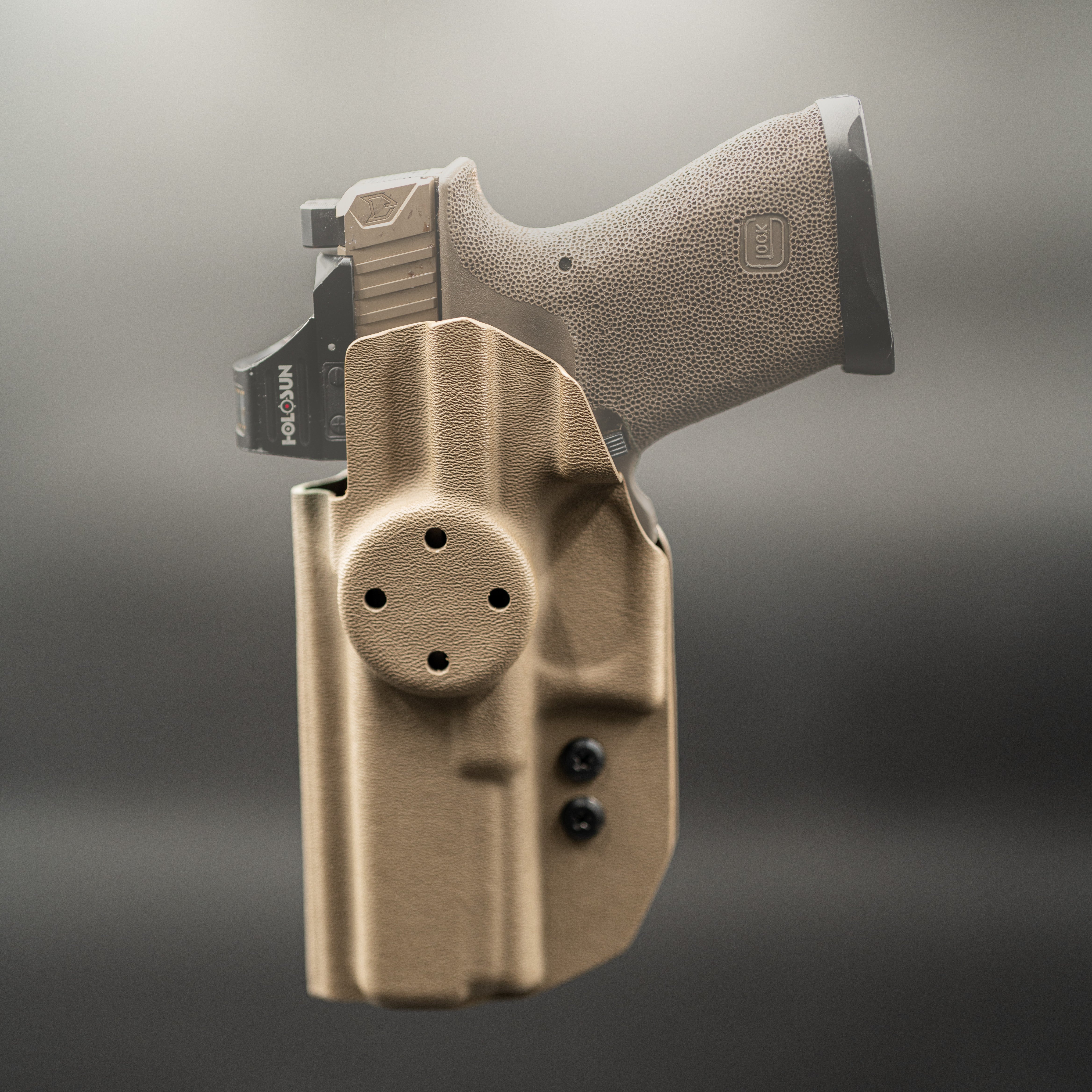 Pistol with a tan holster on a gray background