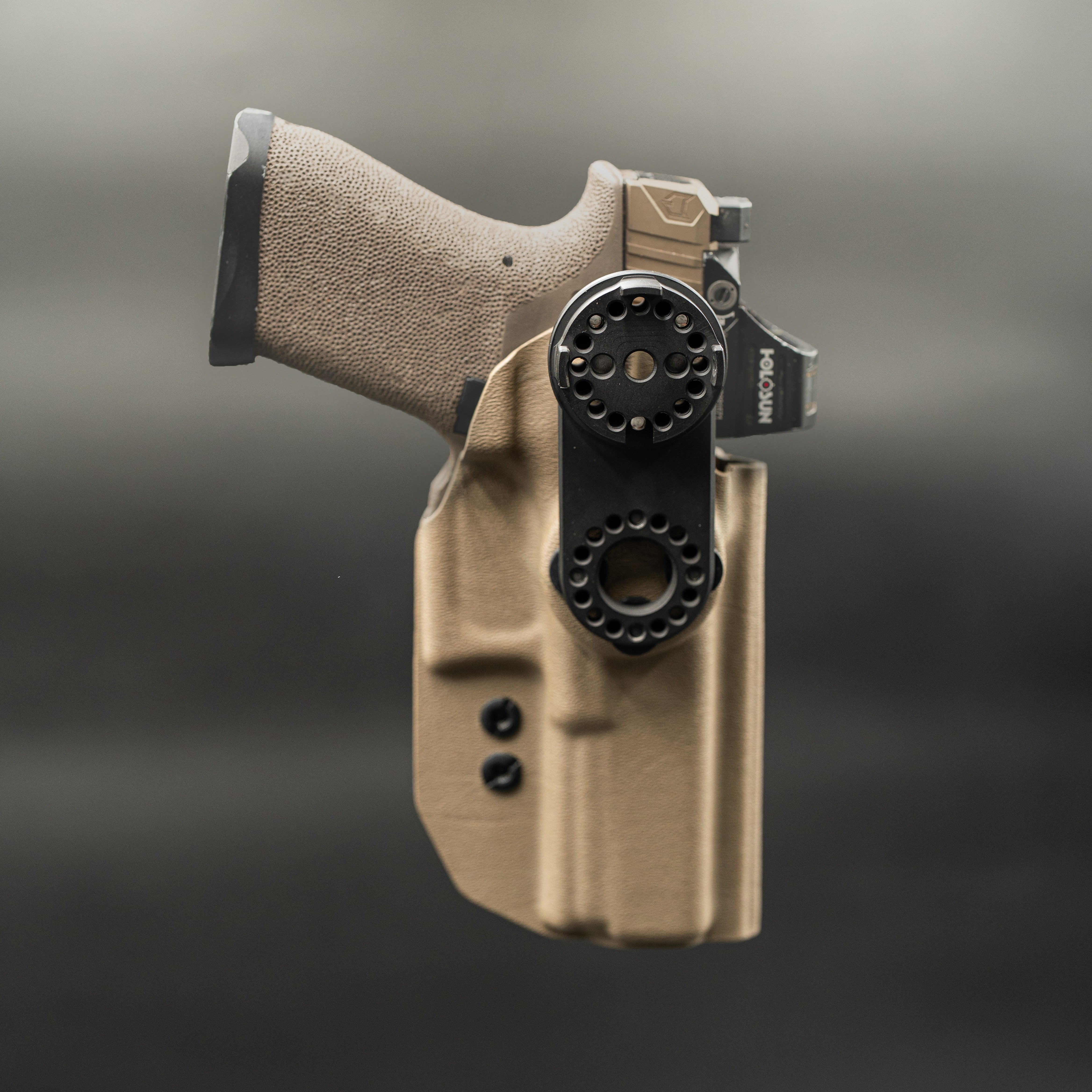 Tan gun holster with a black gun inside on a dark background