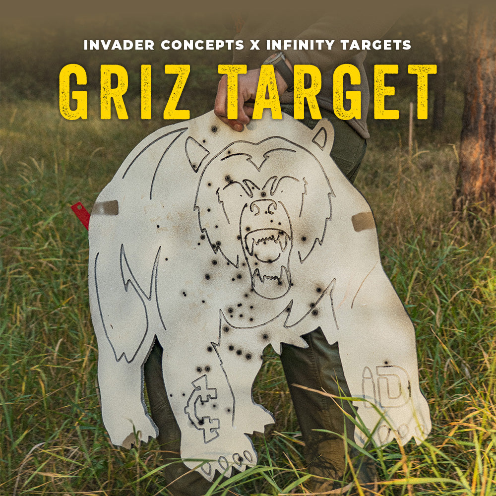 A large white grizzly bear silhouette target with black line art and bullet-hole effects, held outdoors in tall grass. The top of the image has text reading 'INVADER CONCEPTS X INFINITY TARGETS' and 'GRIZ TARGET' in large yellow letters.